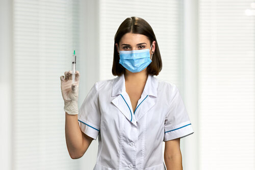 врач в маске со шприцом в руке
