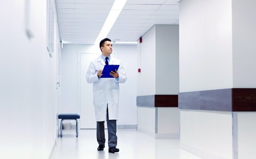 врач с планшетом в руках идет по коридору